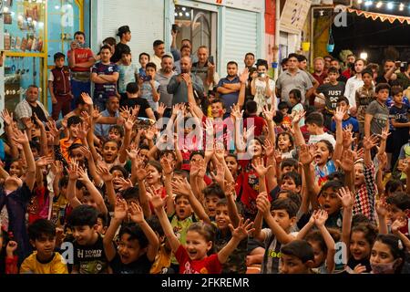 Iraqi Children interagieren mit einem italienischen Clown, der eine Unterhaltungsshow für sie vorführt.eine Unterhaltungsshow wird vom italienischen Clown Marco Rodari inszeniert, Bekannt als Claun il Pimpa für Kinder in der Hammam Al-Manqusha-Gegend in der Altstadt von Mossul, um ihnen zu helfen, mit den Auswirkungen des Krieges und der Besetzung der Stadt durch den IS (Islamischer Staat des Irak und Syrien) fertig zu werden. Die Show fand in dieser fröhlichen blauen Gasse statt, die vor kurzem von Jugendlichen Freiwilligen neu organisiert und arrangiert wurde, um eine wunderschöne Fassade des Gebiets zu werden, das sich nach der Zerstörung durch den letzten Krieg erholt hat. Stockfoto