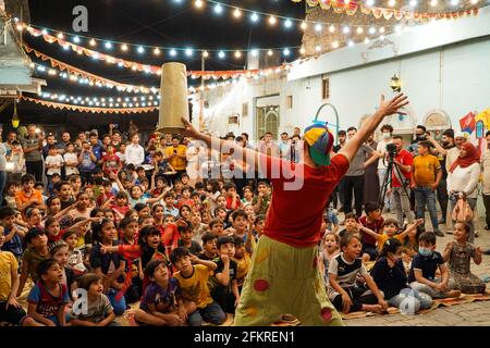 Iraqi Children interagieren mit einem italienischen Clown, der eine Unterhaltungsshow für sie vorführt.eine Unterhaltungsshow wird vom italienischen Clown Marco Rodari inszeniert, Bekannt als Claun il Pimpa für Kinder in der Hammam Al-Manqusha-Gegend in der Altstadt von Mossul, um ihnen zu helfen, mit den Auswirkungen des Krieges und der Besetzung der Stadt durch den IS (Islamischer Staat des Irak und Syrien) fertig zu werden. Die Show fand in dieser fröhlichen blauen Gasse statt, die vor kurzem von Jugendlichen Freiwilligen neu organisiert und arrangiert wurde, um eine wunderschöne Fassade des Gebiets zu werden, das sich nach der Zerstörung durch den letzten Krieg erholt hat. Stockfoto