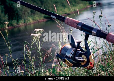 Am Ufer des schönen Flusses über dem Wasserzubringer installiert - Englisch Angelgerät für den Fang von Fischen bequem mit der Rute und der Haspel. Stockfoto