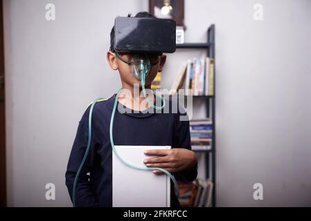 Schuljunge mit Virtual Reality-Headset, das Buch hält und inhalieren lässt Vernebler Stockfoto