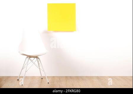 Ein leerer Stuhl im Loft-Stil auf Holzboden mit leerem Werbeplakat und weißem Wandhintergrund, gelber Aufkleber mit Platz für Ihre Texte. Interview Stockfoto