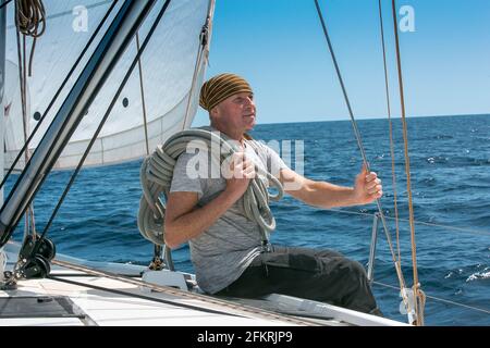 Ein Mann an Bord einer Segelyacht auf See. Yachting. Aktives Lifestyle-Konzept. Stockfoto