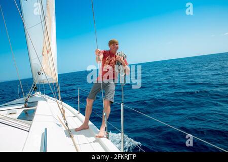 Ein Mann an Bord einer Segelyacht auf See. Yachting. Aktives Lifestyle-Konzept. Stockfoto