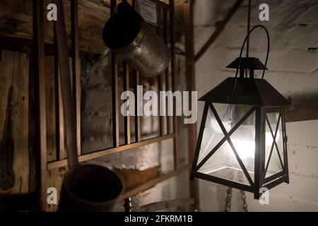 Kirzhach, Region Wladimir, Russland - April, 2021: Eine antike Lampe mit einer elektrischen Lampe hängt an der Wand eines Holzhauses. Stockfoto