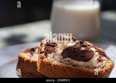 Nahaufnahme der Marmorkuchenscheibe auf weißem Teller Und Holztisch Stockfoto