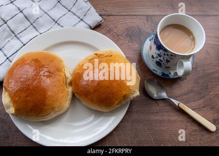 Gebackene Char siu bao oder BBQ Schweinebraten auf einem Tisch serviert mit einer Tasse Milchtee. Stockfoto