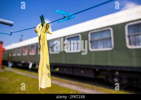 28. April 2021, Mecklenburg-Vorpommern, Pasewalk: Ein gelber Mopp hängt an der Linie vor den hier parkenden ehemaligen Saloon- und Speisewagen des ehemaligen DDR-Regierungszugs. Das Eisenbahn-Erlebniszentrum Lokschuppen Pommern ist aufgrund der Corona-Schutzmaßnahmen seit Monaten geschlossen. Auf dem 40,000 Quadratmeter großen Gelände mit seinem historischen Triebwerksschuppen aus dem Jahr 1896 konnten die Besucher die Bahntechnik mit mehreren Dampf- und Dieselloks bestaunen. Der Lokschuppen feiert 2021 ein besonderes Jubiläum: Er wird 125 Jahre alt. Ob und in welcher Form es gefeiert werden kann Stockfoto