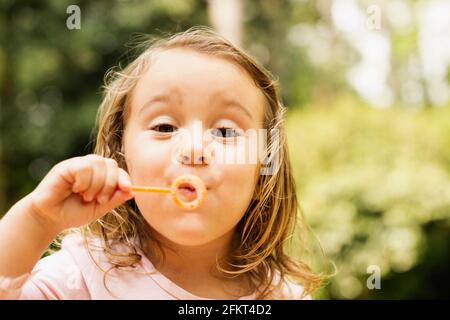 Porträt von weiblichen Kleinkind Seifenblasen im Garten hautnah Stockfoto