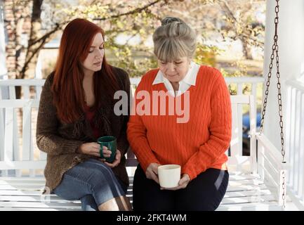 Ältere Frau und Erwachsene Tochter mit ernsthaften Diskussionen auf der Veranda Stockfoto