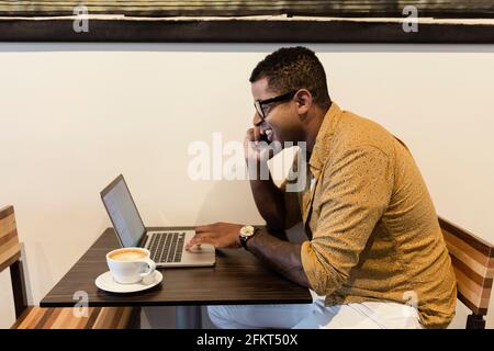 Junger Mann im Coffee-Shop, mit Laptop und smartphone Stockfoto