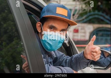 Menschen tragen Gesichtsmaske im Auto, Mann tragen medizinische Maske im Auto, Maske schützen covid19 Coronavirus Stockfoto