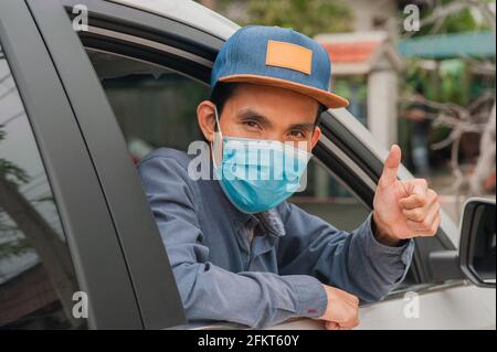 Menschen tragen Gesichtsmaske im Auto, Mann tragen medizinische Maske im Auto, Maske schützen covid19 Coronavirus Stockfoto