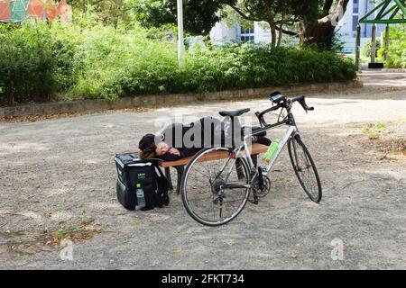 Ein Uber isst einen Kurier, der zwischen den Lieferungen in Nagoya, Japan, eine Pause macht. Stockfoto