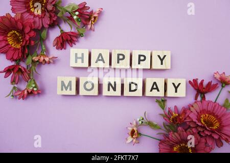 Happy Monday Buchstaben mit Blumendekoration von oben auf lila Hintergrund Stockfoto