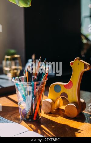 Holzspielzeug Giraffe, Buntstifte und ein Malbuch auf einem Holztisch. Stockfoto