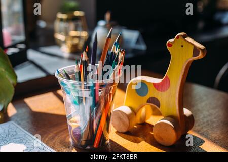 Holzspielzeug Giraffe, Buntstifte und ein Malbuch auf einem Holztisch. Stockfoto
