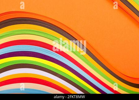 Curl Regenbogen Streifen Papier auf orangefarbenem Hintergrund. Stockfoto