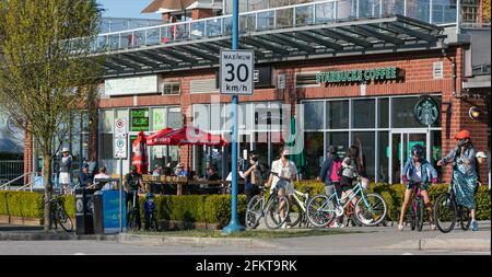 Straßenansicht der Menschen mit Gesichtsmasken, die auf dem Bürgersteig der Straße in Guilford, BC, spazieren und Fahrrad fahren Stockfoto