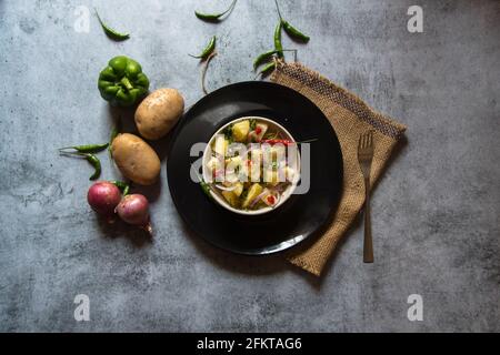 Indische Snacks Aloo jeera oder Kartoffelpüree mit Pfeffer und gehackten Zwiebeln gemischt. Draufsicht, selektiver Fokus. Stockfoto