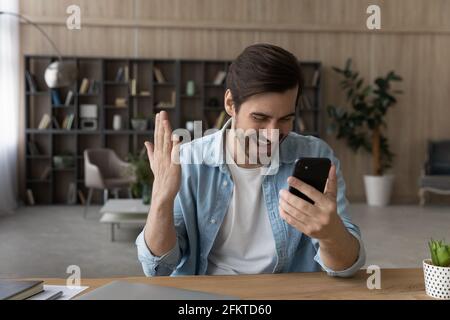 Überglücklich überrascht Mann lesen gute Nachrichten in Nachricht, mit Smartphone Stockfoto