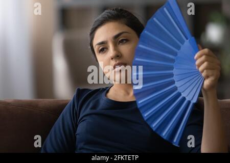 Nahaufnahme müde überhitzte indische Frau winkende Papierfächer Stockfoto