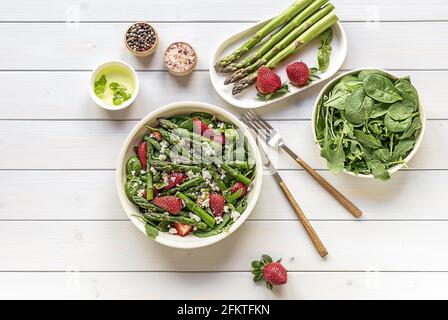 Ein gesunder und köstlicher Salat aus frischen Erdbeeren, grünem Spargel, Feta-Käse mit Gemüseblättern. Stockfoto