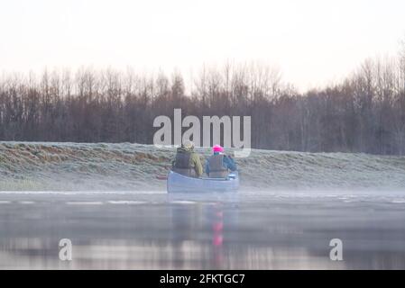 Mann rudert im frühen Frühjahr am frühen Morgen ein Kanu. Lifestyle. Morgenlandschaft, Nebel am Morgenfluss und Menschen im Kanu Stockfoto