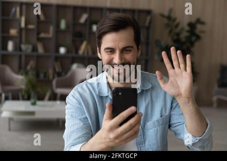 Nahaufnahme lächelnder Mann winkt Hand an Smartphone-Webcam, chattet Stockfoto