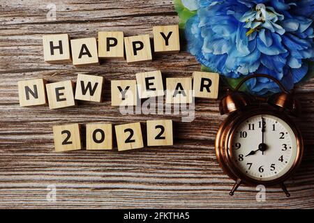 Happy New Year 2022 mit Wecker auf hölzernem Hintergrund Stockfoto