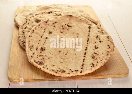 Mehrere frisch gebackene Pita-Brote auf einem Bambusbrett, Nahaufnahme, auf einem Holztisch. Stockfoto