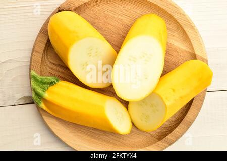 Ein reifes, biologisches, gelbes Pflanzenmark, aus nächster Nähe, auf einem runden Bambustablett auf einem Holztisch, Draufsicht. Stockfoto