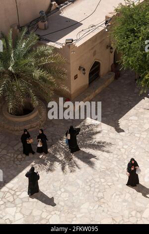 Luftaufnahme von weiblichen Touristen in schwarzem abaja in einem Innenhof im Nizwa Fort. Region Ad Dakhiliyah, Oman Stockfoto