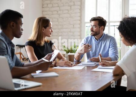 Selbstbewusster junger männlicher Führer, der Verhandlungssitzung führt. Stockfoto