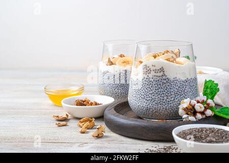 Natürlich, reich an Vitamin, Kalzium und Omega 3 Pudding mit Chiasamen, Nüssen und Honig auf hellem Holzgrund. Seitenansicht, Kopierbereich. Stockfoto
