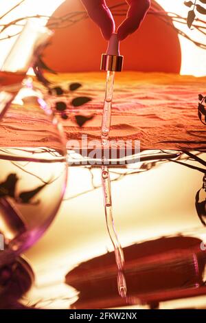 Pipette mit feuchtigkeitsspendendem Serum. Vor dem Hintergrund einer dekorativen Wüstenlandschaft. Stockfoto