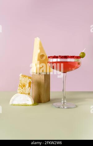 Stillleben von Rosenwein, Käse und Honig in Kämmen. Vorderansicht auf hellrosa und grünem Hintergrund. Stockfoto