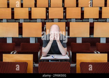 Müde gestresster Student Mann in leerem Uni-Klassenzimmer. Alopezie, ängstlich Stockfoto