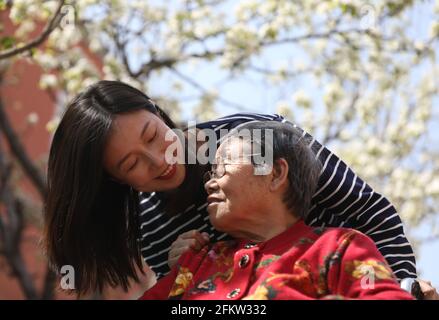 (210504) -- SHENYANG, 4. Mai 2021 (Xinhua) -- Chen Si begleitet eine ältere Frau im Pflegeheim Tianzhushan in Shenyang, der Hauptstadt der nordöstlichen Provinz Liaoning, am 21. April 2021. Chen Si, 34, schloss sein Studium an der Harvard University ab. 2013 gab sie ihren Job an der Wall Street auf und kehrte in ihre Heimatstadt zurück. Und dann begann sie eine Vollzeitstelle als Direktorin eines Pflegeheims.Zuerst verstanden viele nicht, warum eine junge Dame wie sie eine solche Entscheidung traf und zweifelte, ob sie sich gut um ältere Menschen kümmern könnte. Es gibt fast 500 ältere Menschen in der Pflegehalle Stockfoto