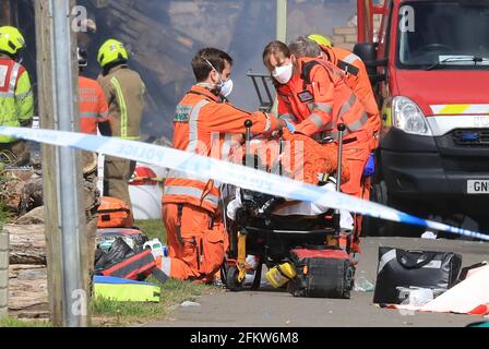 Sanitäter betreuen eine verletzte Person am Ort eines Hausbrandes in Mill View in Willesborough, nahe Ashford, Kent, nach einer gemeldeten Explosion. Bilddatum: Dienstag, 4. Mai 2021. Stockfoto