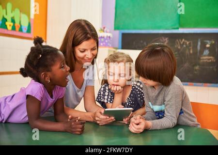 Pädagoge und Kinder mit Tablet-Computer online im Kindergarten oder Vorschule Stockfoto