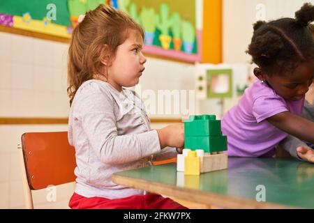 Mädchen im internationalen Kindergarten oder in der Vorschule spielen mit Bausteinen Am Tisch Stockfoto