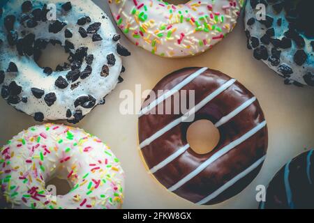 Flach legen Bild von Donut mit Schokolade Glasur mit Streifen amids anderen verschiedenen Donuts Stockfoto