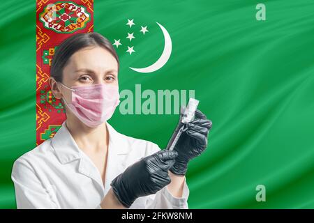 Die Ärztin bereitet die Impfung vor dem Hintergrund der Turkmenistan-Flagge vor. Impfung in Turkmenistan. Stockfoto