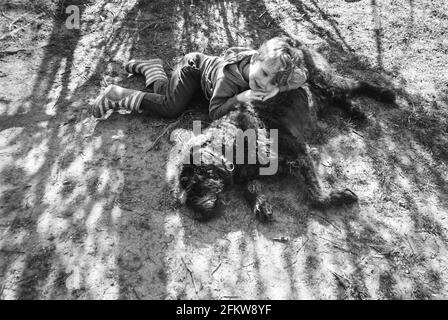 Vierjähriger Junge mit seinem Hund Labradoodle, Medstead, Hampshire, England, Vereinigtes Königreich. Stockfoto