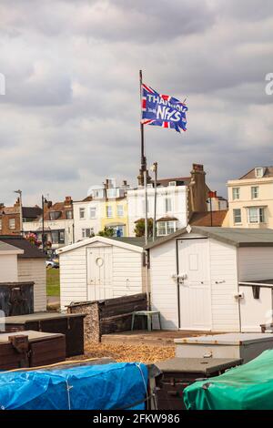 Fischerhütten mit der NHS-Flagge am Strand von Deal, Kent, Großbritannien Stockfoto