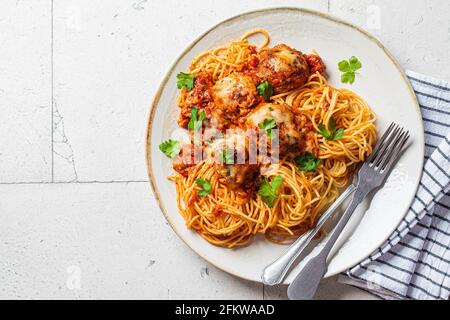 Spaghetti mit Fleischbällchen, Käse und Tomatensauce in einem weißen Gericht. Stockfoto
