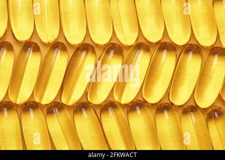 Fischöl-Softgels in einer Reihe, Omega 3 Kapseln, gelber geometrischer Hintergrund. Stockfoto