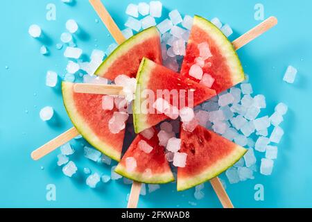 Wassermelone schneidet die Eiszapfen auf blauem Hintergrund Stockfoto