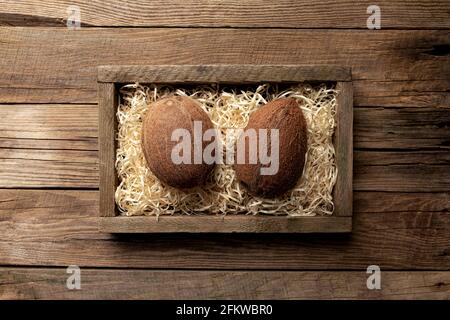 Frische tropische Kokosnussfrüchte in einer Holzlieferbox auf einem Holzhintergrund. Gesundes Essen Konzept Draufsicht Flat Lay mit Kopieplatz für einige Werbung Stockfoto