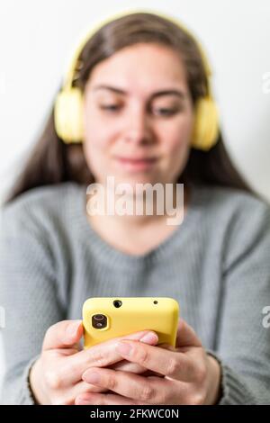 Junge Frau mit kabellosen gelben Kopfhörern Stockfoto